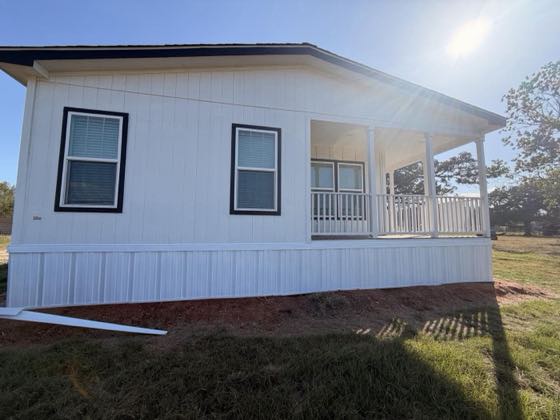 A white home with a covered front porch and white railing, finished with white skirting.