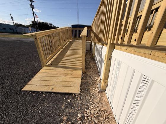 A wooden wheelchair ramp running alongside freshly fitted white skirting.