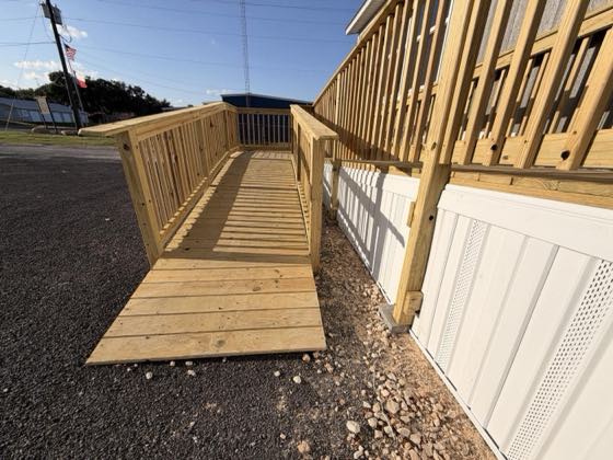 A wheelchair ramp and landing beside white skirting with ventilation panels.