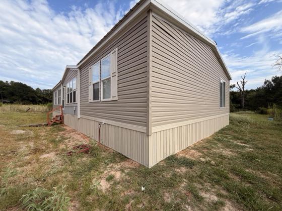 A cream home with cream skirting wrapping the full corner on a green lot.